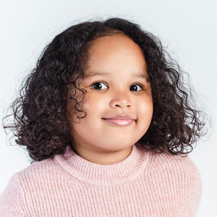 Petite fille aux cheveux bouclés qui sourit